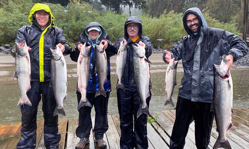 salmon-group-columbia-River-fishing-guide People holding fish on a dock, smiling and enjoying their catch together with Columbia River fishing guide