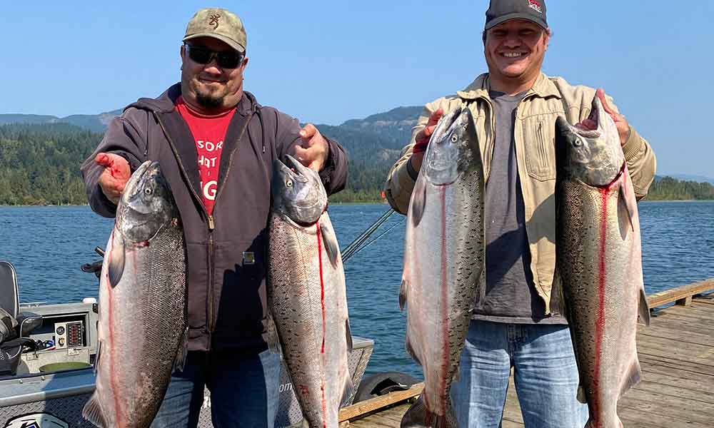 salmon-group-columbia-River-fishing-guide People holding fish on a dock, smiling and enjoying their catch together with Columbia River fishing guide