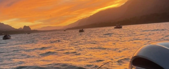 Sunset over the Columbia River with a fishing rod in the foreground and a Yamaha boat engine visible.